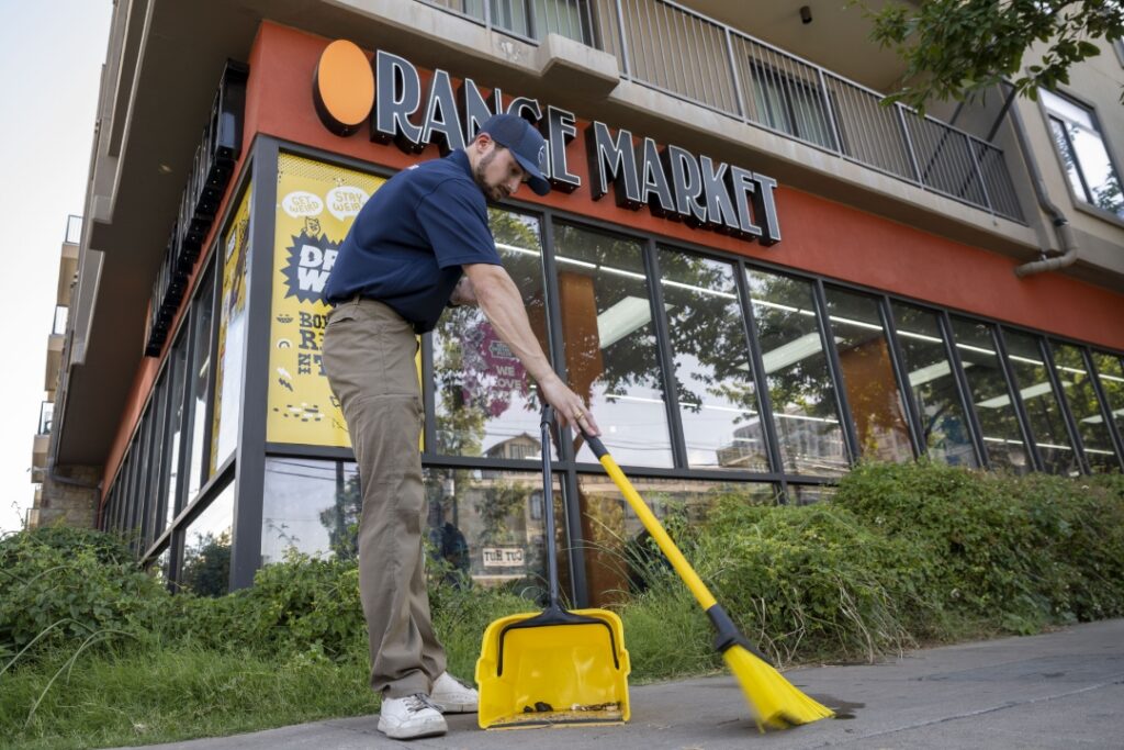 West Campus Ambassador sweeping in front of Range Market